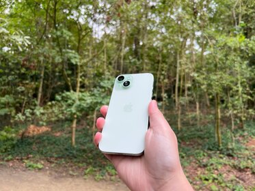 iPhone 15 review in groen in bos