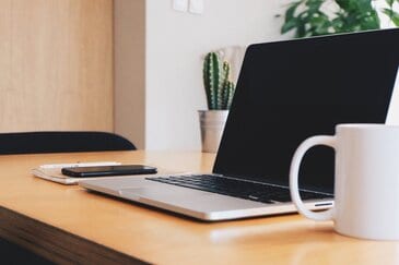 Tips voor thuiswerken: MacBook, iPhone en meer op bureau.