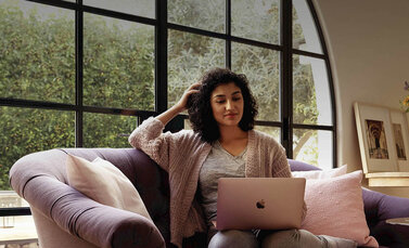 Vrouw op bank met MacBook gebruikt personal hotspot