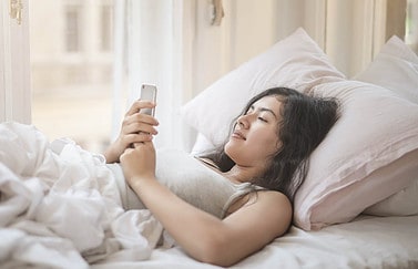 Vrouw in bed: muziek als wekker gebruiken