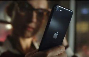 Vrouw met iPhone SE 2022 vanaf achterkant.