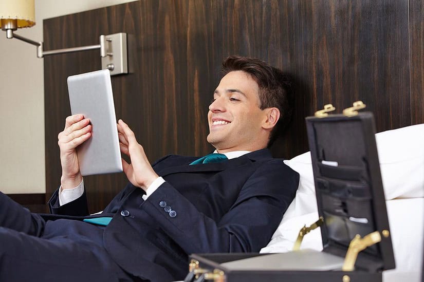 Successful business man working with tablet PC in his hotel room (c) Robert Kneschke/Shutterstock
