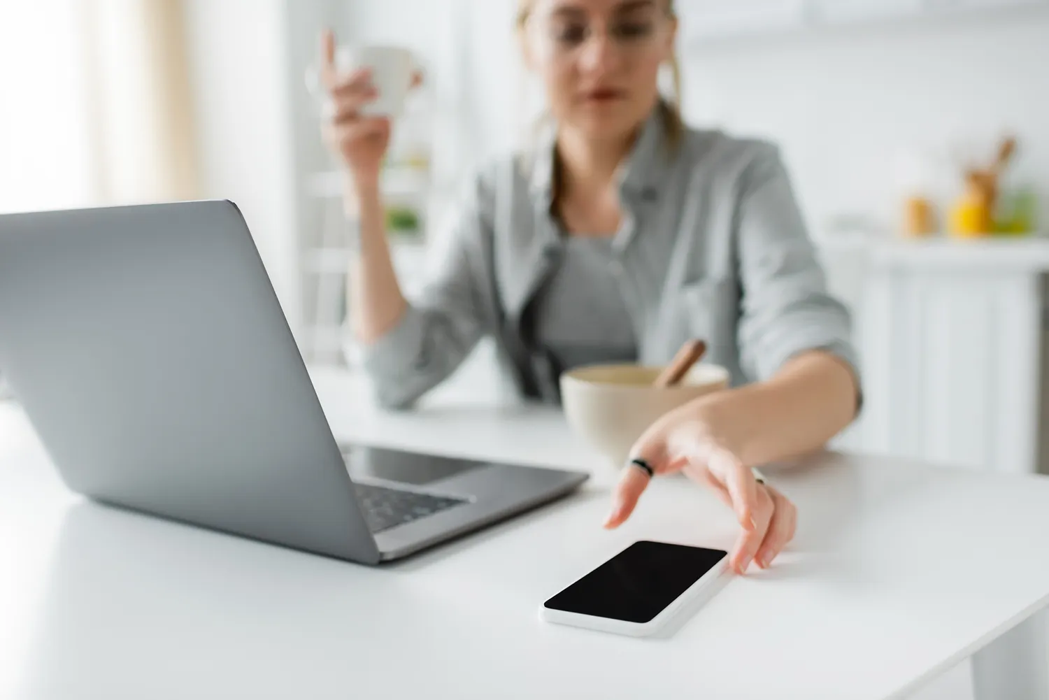 Vrouw grijpt naar smartphone achter bureau