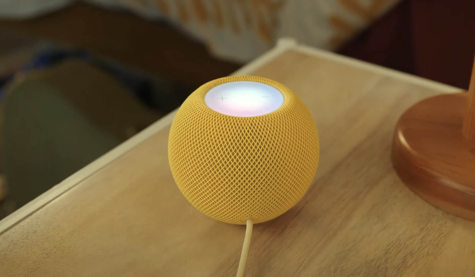 Gele HomePod mini die muziek afspeelt.